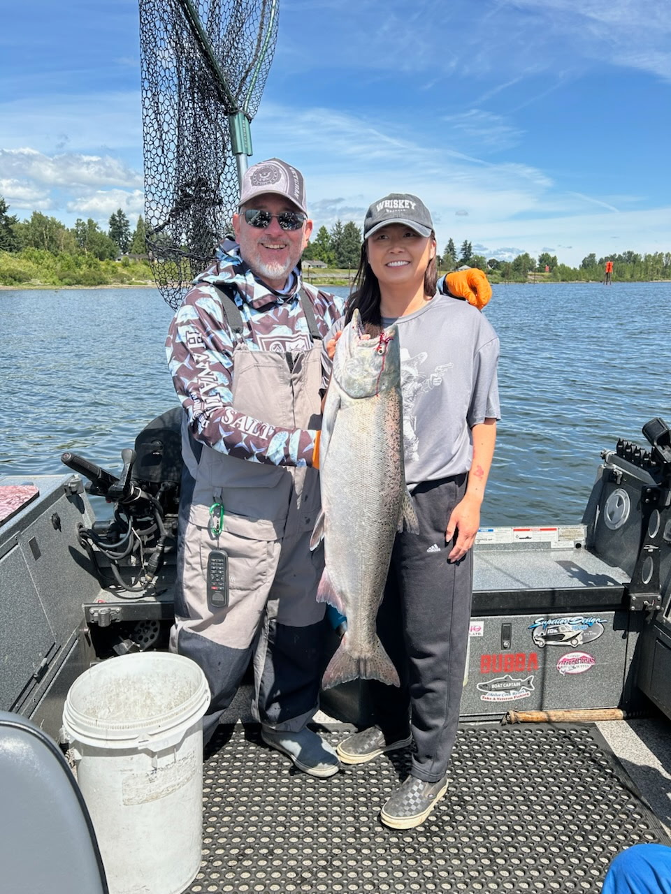 Tony Owsian and a client holding a bright chrome Chinook salmon on the Columbia River, blue sky day.