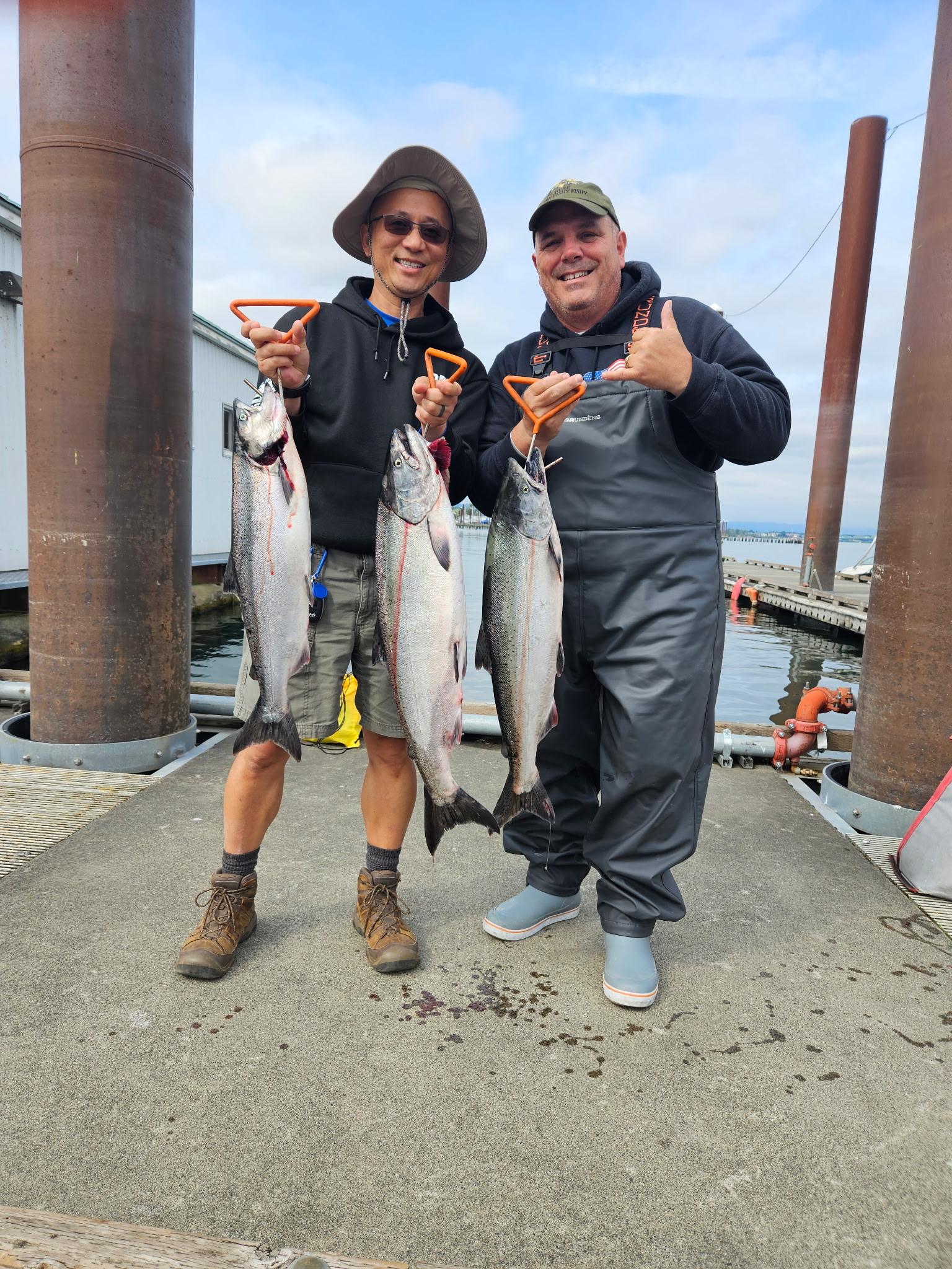 Two anglers holding Chinook salmon at the dock with weathered pilings, lower Columbia River near Astoria.