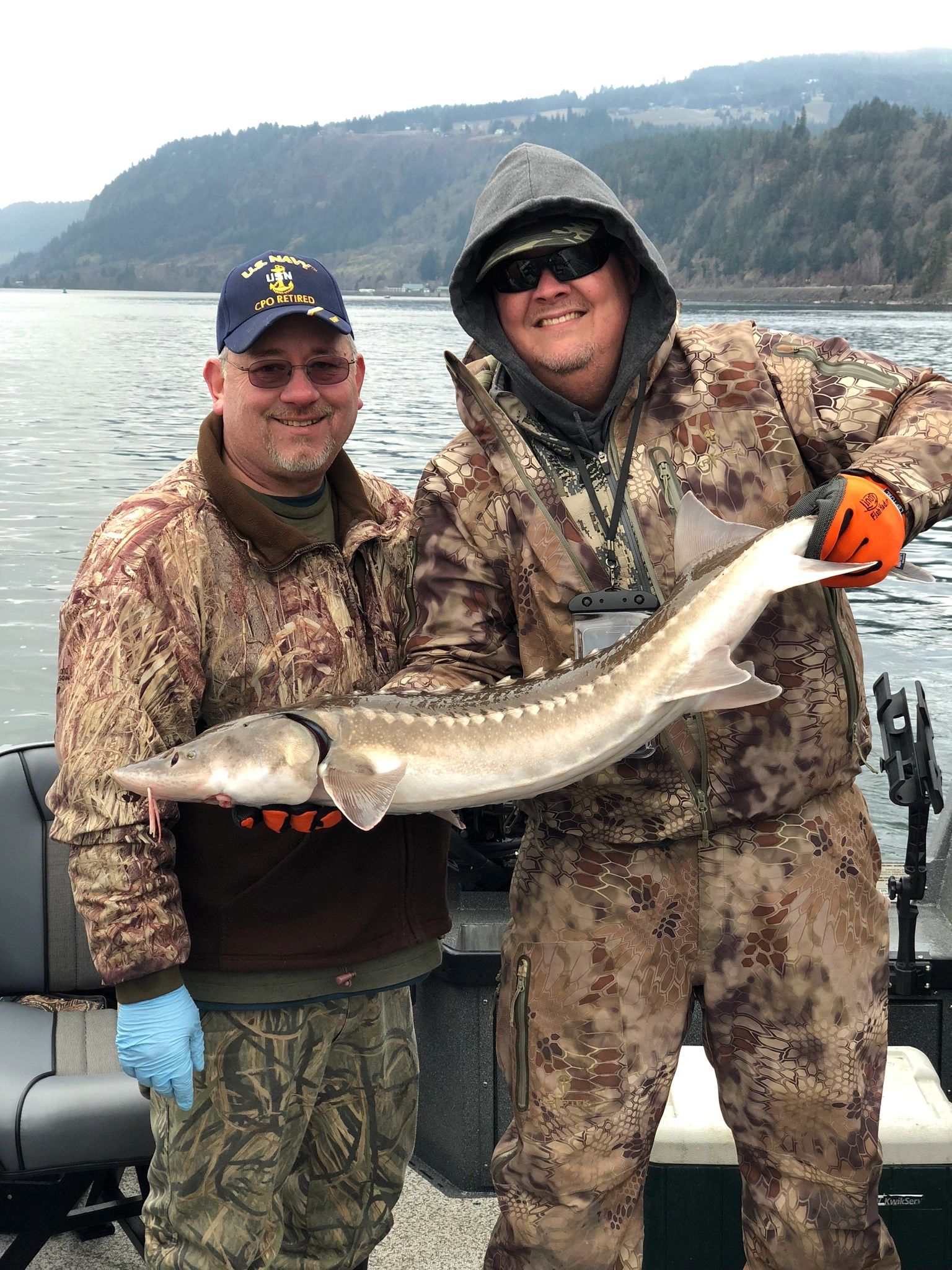 Tony Owsian and a client in camouflage holding a Columbia River white sturgeon in the Columbia Gorge.